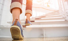 Young adult woman walking up the stairs with sun sport background 
