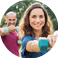 Mature people in training session of aerobics using dumbbells at park  Happy man and smiling woman practicing fitness together outdoor  Portrait of mature woman doing exercise with other people in background 