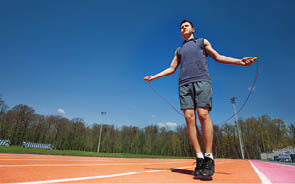 Active teenage athlete skipping the rope outside on the stadium, bottom view