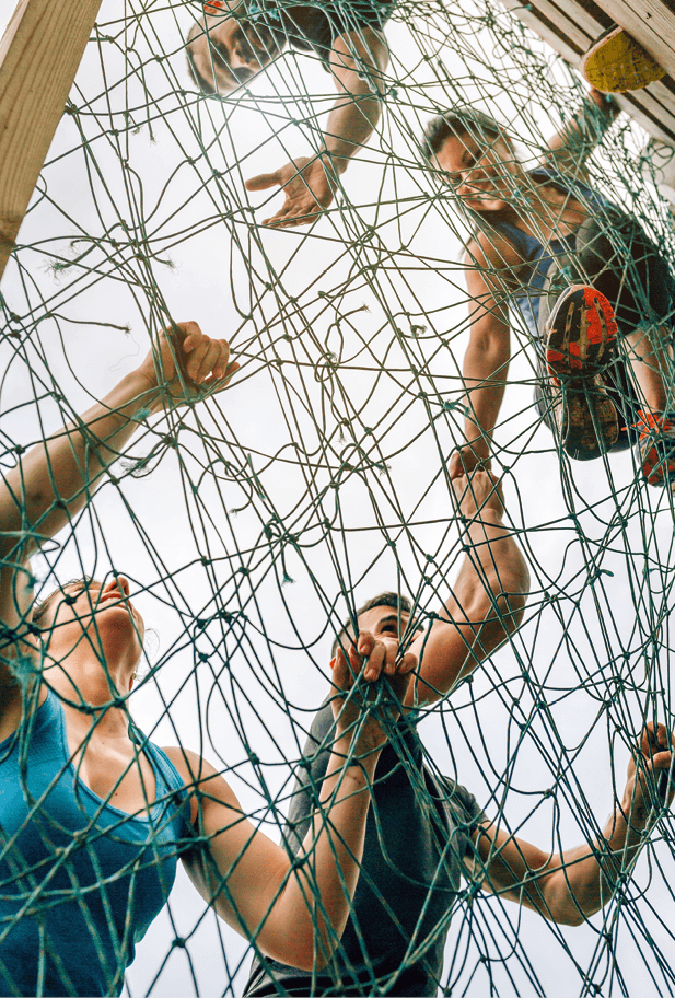 Group of participants in an obstacle course climbing a net