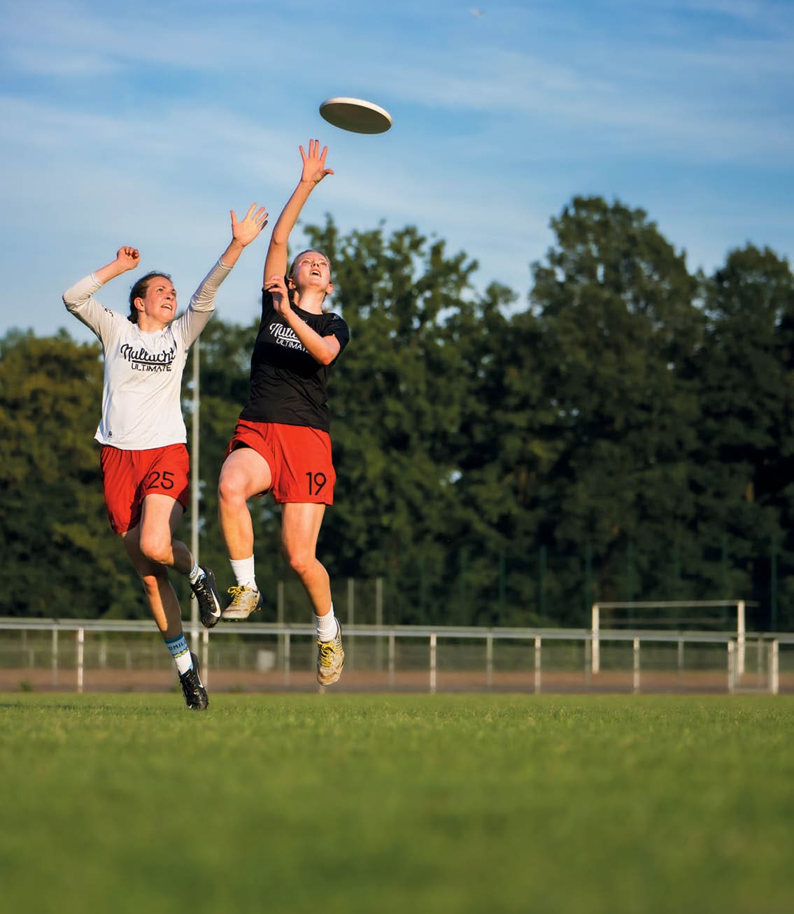 Discogolf - Zwei Frauen springen hoch und versuchen die Frisbee zu fangen