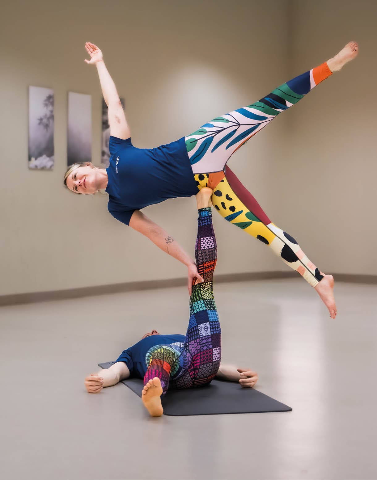 AcroYoga: Eine Frau balanciert auf dem R cken liegend miit ausgestrecktem Bein eine zweite Frau.