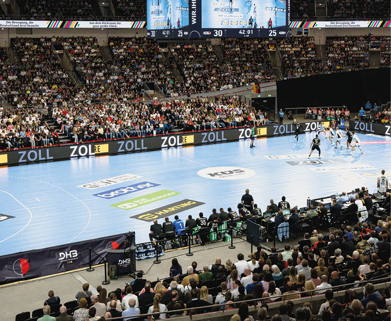 Bild zum Thema Sponsoring einer Handball Halle w hrend eines Spiels. Zu sehen sind die Werbebanner auf  dem Boden und am Spielfeldrand.