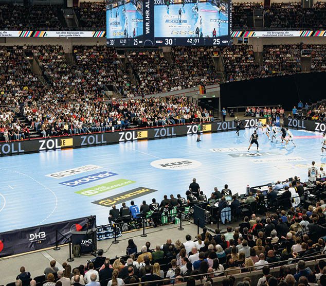 Bild zum Thema Sponsoring einer Handball Halle w hrend eines Spiels. Zu sehen sind die Werbebanner auf  dem Boden und am Spielfeldrand.
