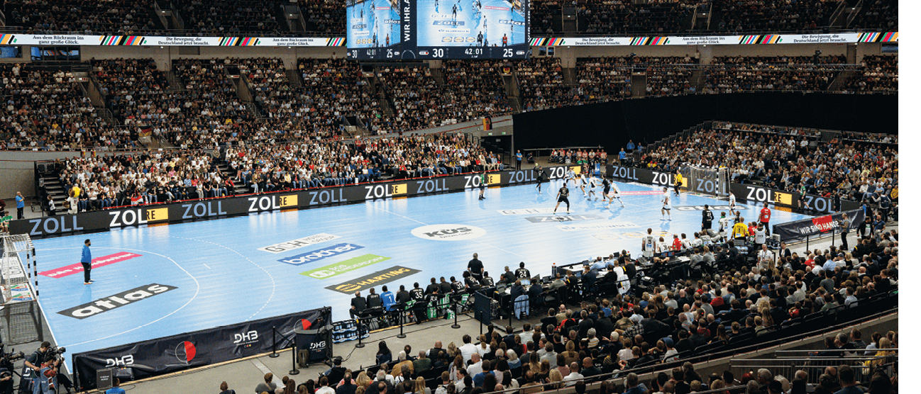 Bild zum Thema Sponsoring einer Handball Halle w hrend eines Spiels. Zu sehen sind die Werbebanner auf  dem Boden und am Spielfeldrand.