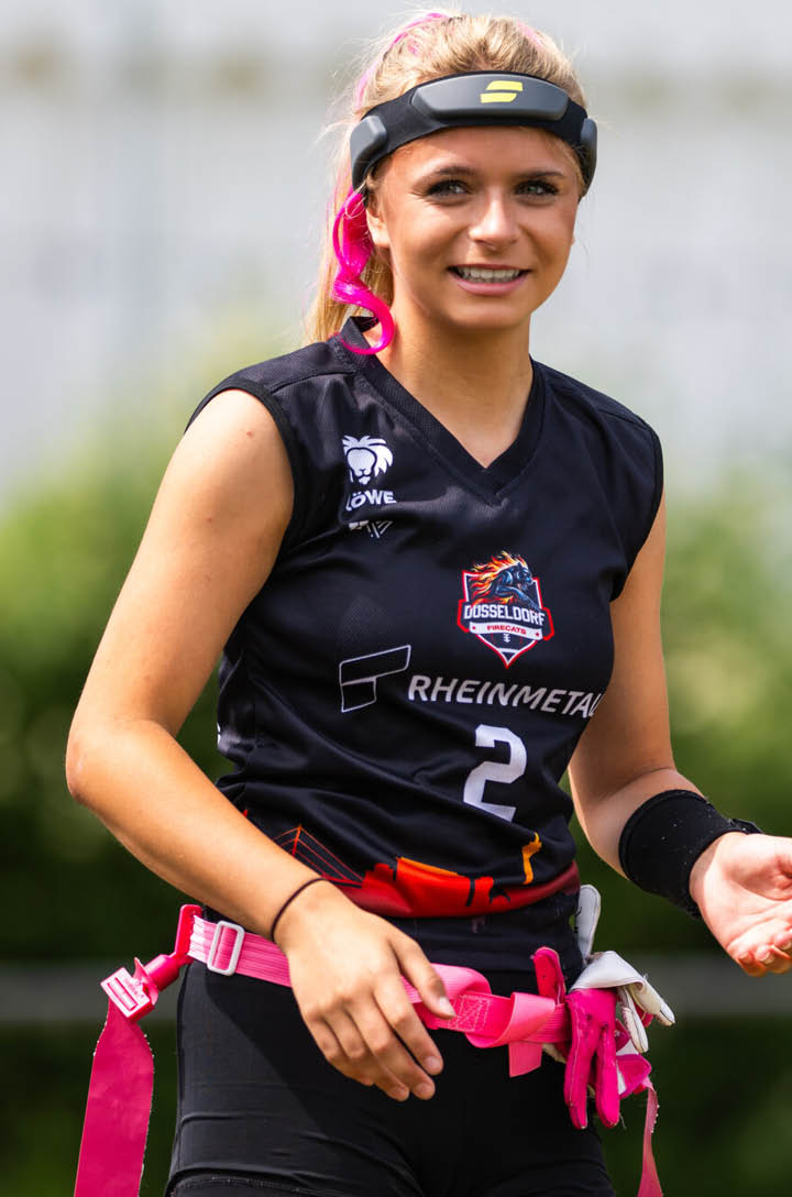 Nika Wiesner mit Stirnband tr gt einen G rtel mit Flaggen und steht auf einem Spielfeld im Freien bereit zum Flag-Football