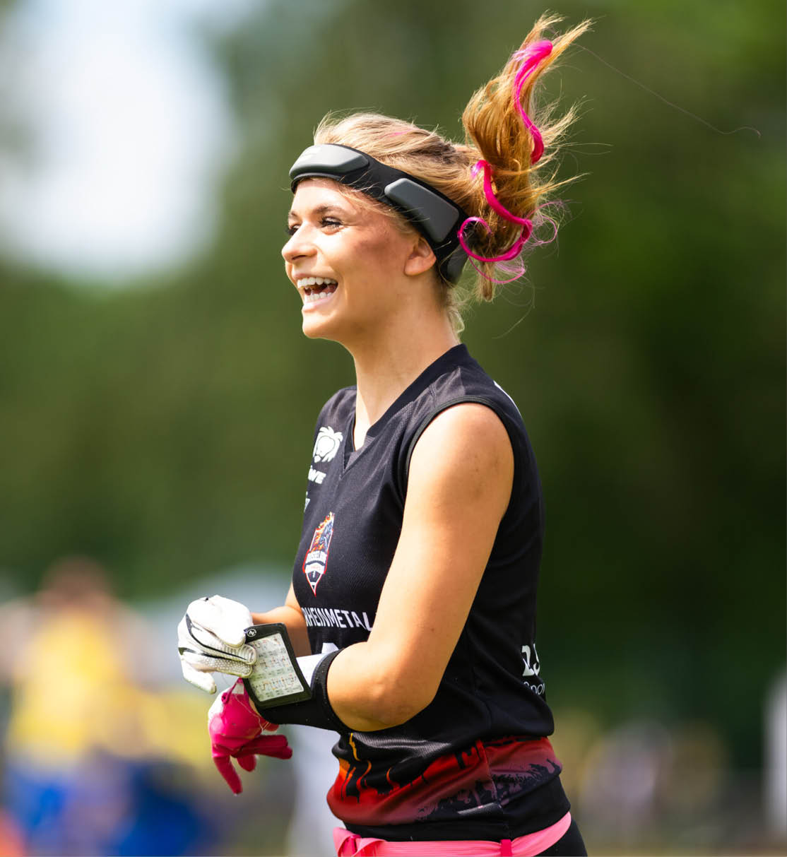 Nika Wiesner, WestLotto TopTalent mit hochgebundenem Haar und pinken Haarstr hnen tr gt sportliche Kleidung und Handschuhe und h lt ein Notizbuch in der Hand.   
