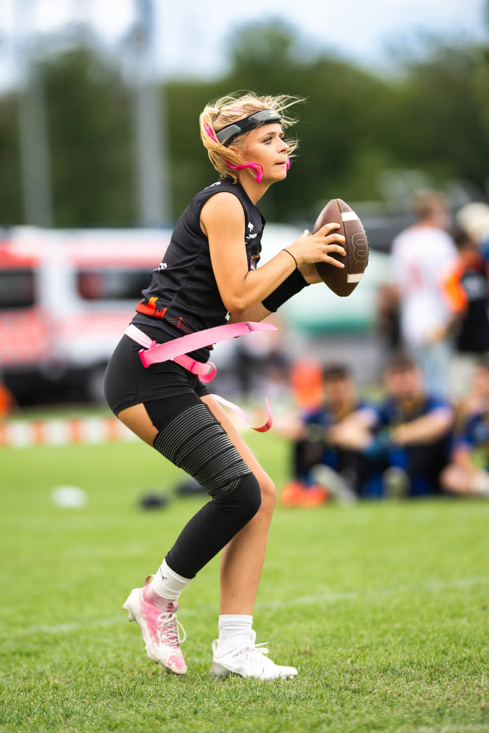 Eine Person in Sportkleidung h lt einen Football in der Hand und steht auf einem Spielfeld mit gr nem Gras. Beschreibung von KI generiert