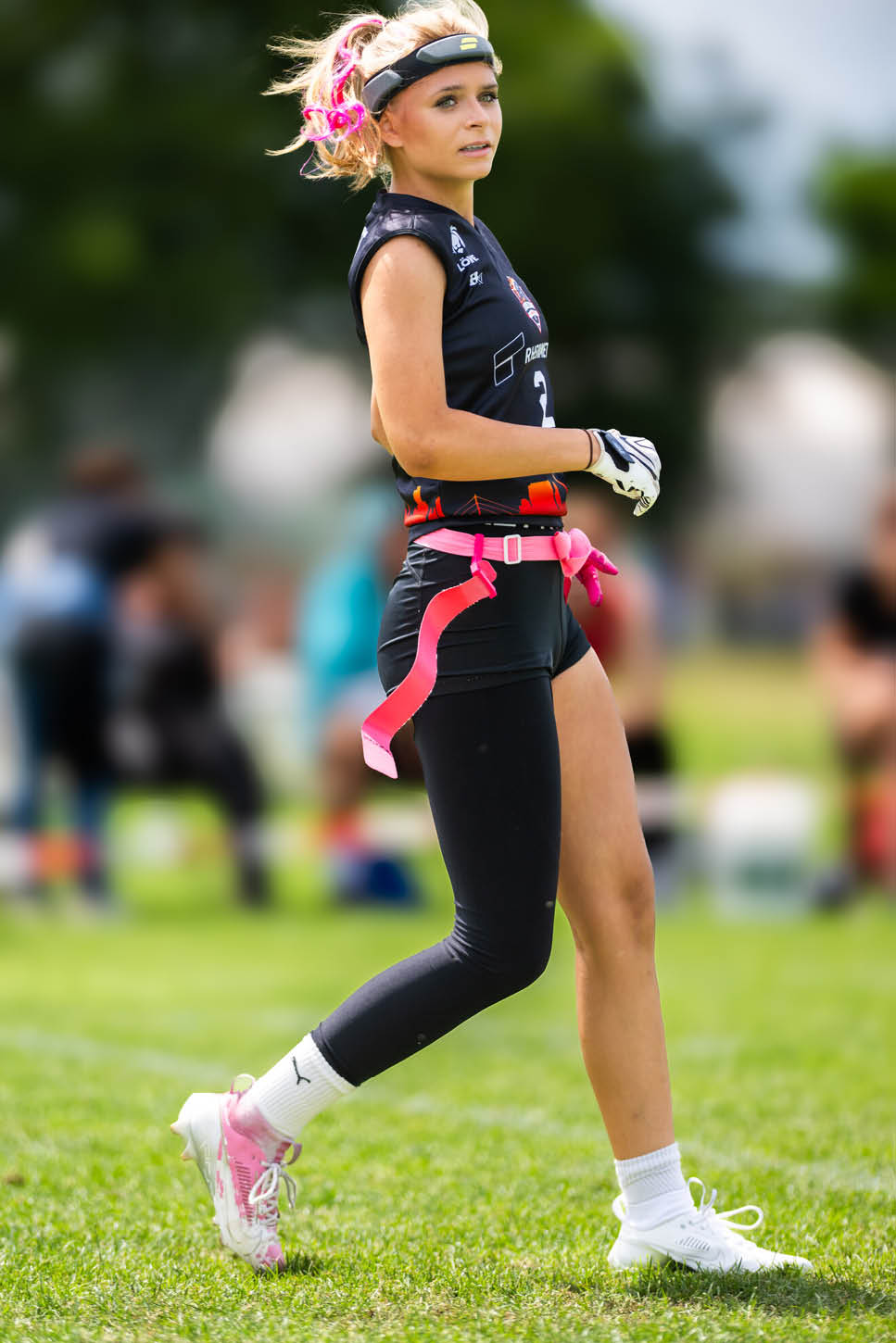 Eine Person mit Sportkleidung und pinken B ndern spielt auf einem gr nen Spielfeld bei Tageslicht. Beschreibung von KI generiert