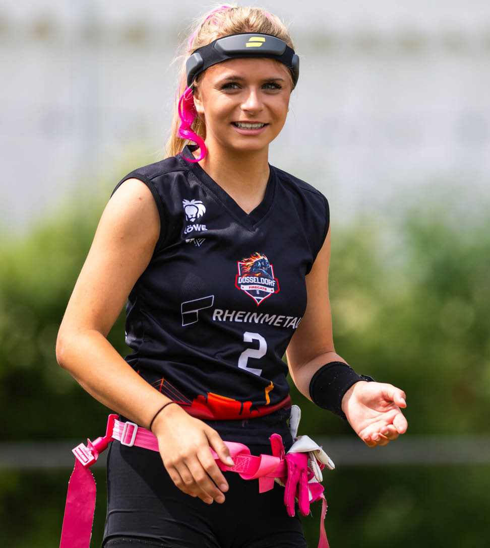 Nika Wiesner mit Stirnband tr gt einen G rtel mit Flaggen und steht auf einem Spielfeld im Freien bereit zum Flag-Football