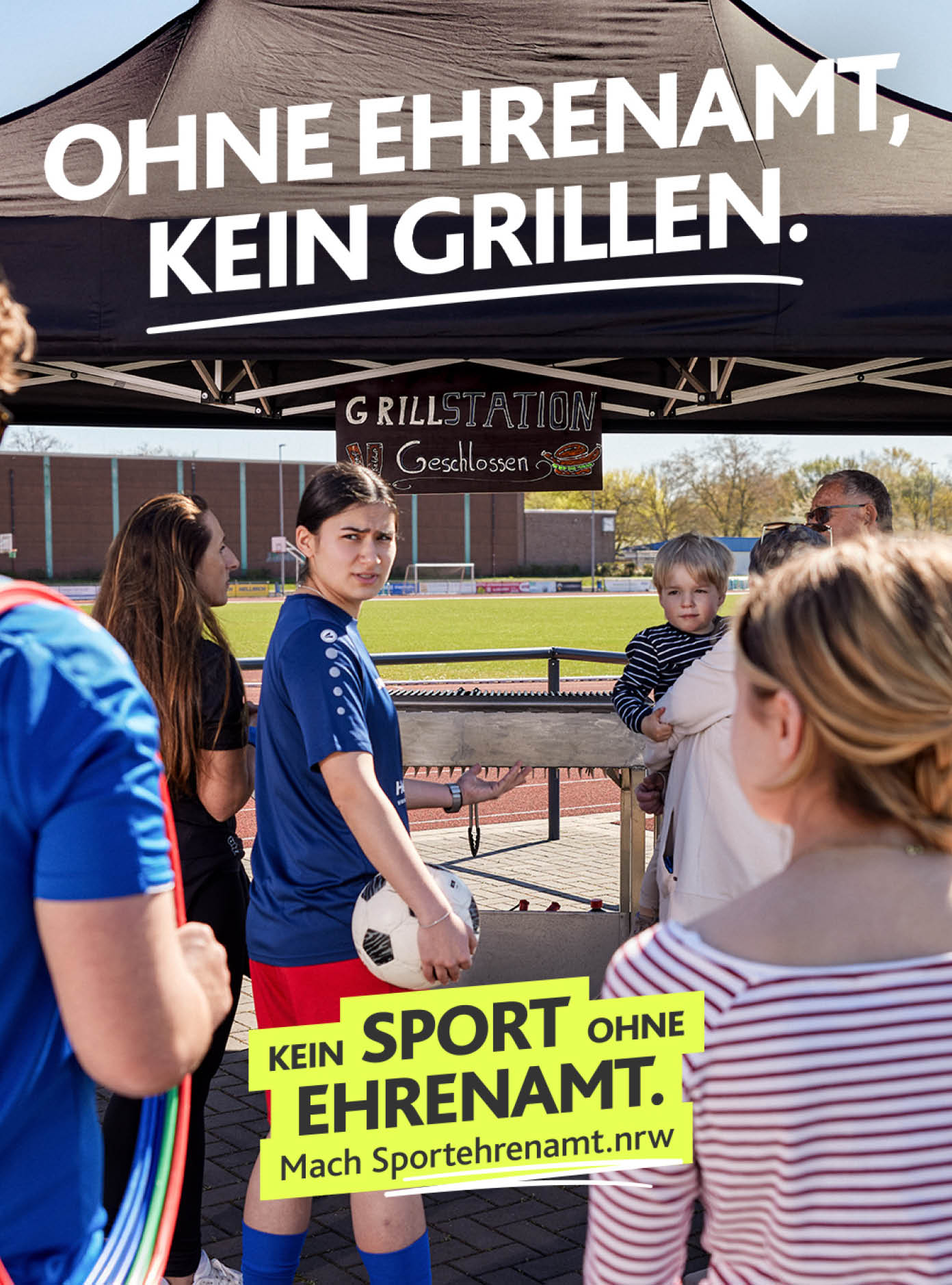Mehrere Personen stehen vor einem Grillstand mit dem Schriftzug „Ohne Ehrenamt, kein Grillen“ und einem weiteren Schild, das f r Sportehrenamt wirbt. Beschreibung von KI generiert