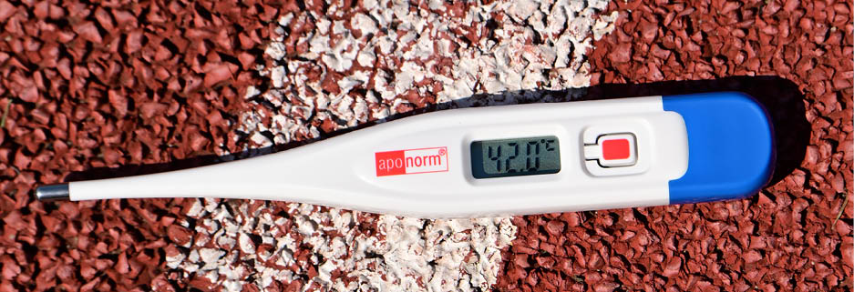Auf der wei en Markierung einer roten Gummilaufbahn liegt ein Thermometer. Die Anzeige zeigt 42,0 °C. 