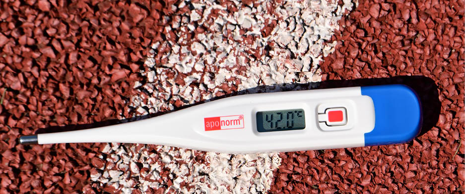 Auf der wei en Markierung einer roten Gummilaufbahn liegt ein Thermometer. Die Anzeige zeigt 42,0 °C. 